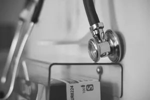 Otwarte podręczniki optometryczne z okularami na drewnianym biurku, symbolizujące naukę o wzroku i korekcję dalekowzroczności.